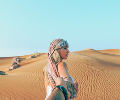 man and woman holding hands while in desert