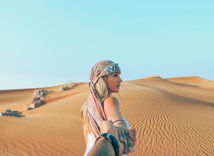 man and woman holding hands while in desert