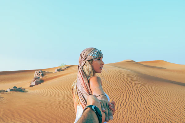 Two people holding hands while walking in the desert
