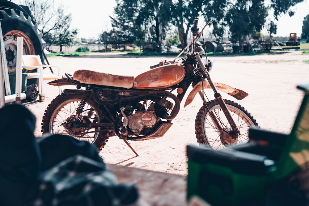 brown dirt bike parked near empty lot at daytime