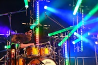 A drummer in action, surrounded by colorful stage lights.