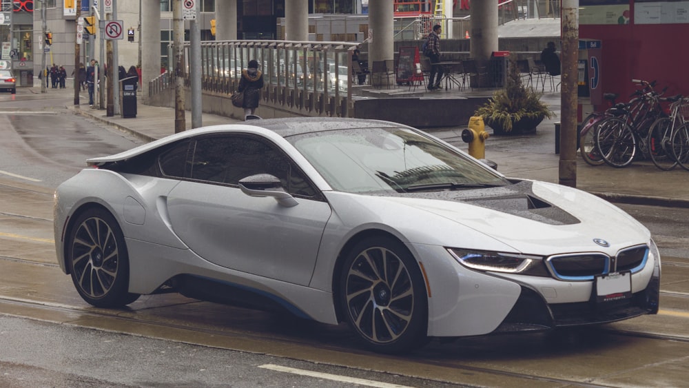 white BMW coupe near man and buildings