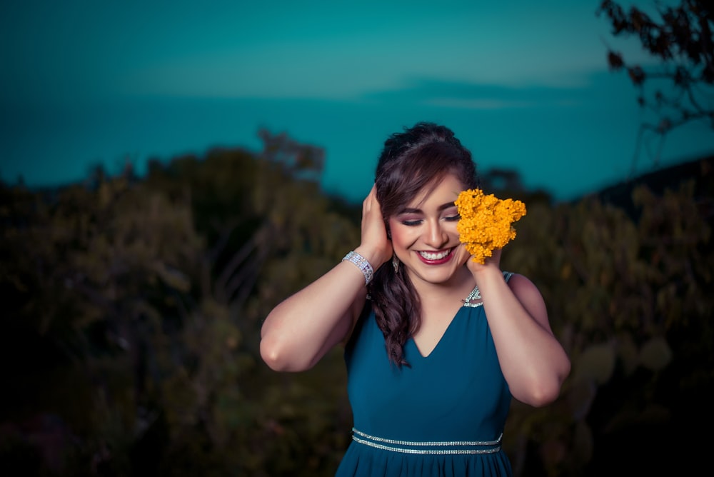 Frau berührt ihr Haar, während sie orangefarbene Blumen hält