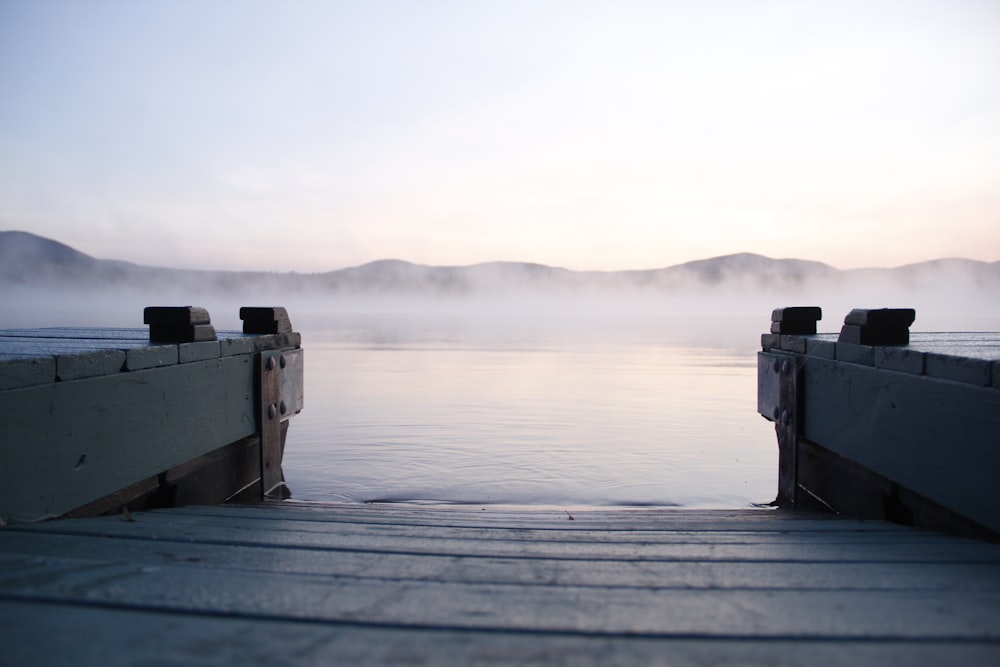 pontile di legno grigio vicino allo specchio d'acqua