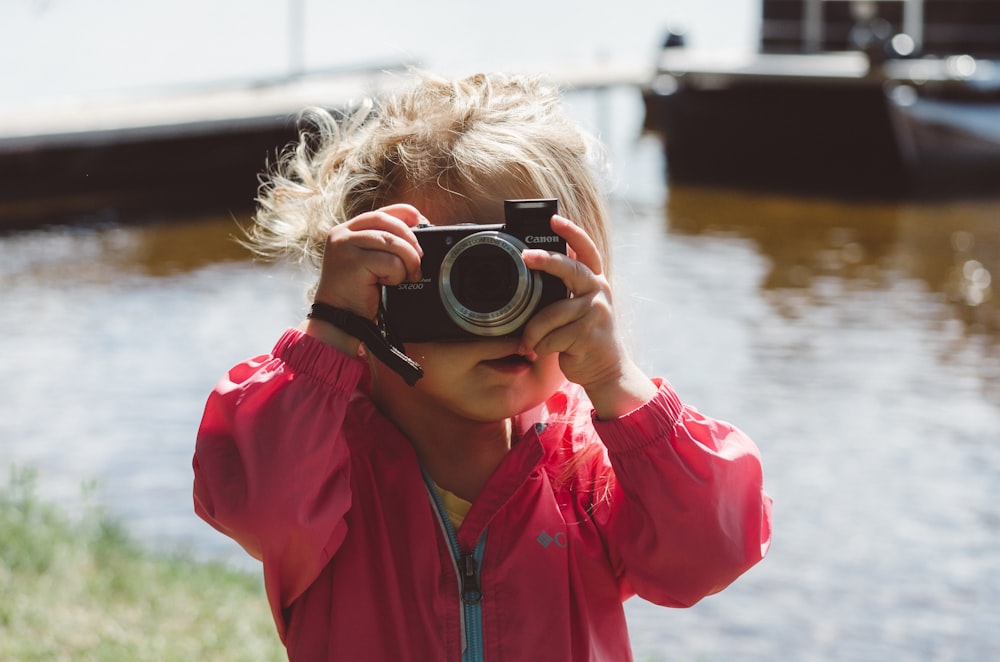 selective focus photography of girl using a camera