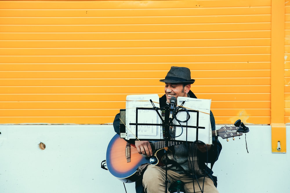 homem tocando violão marrom e preto