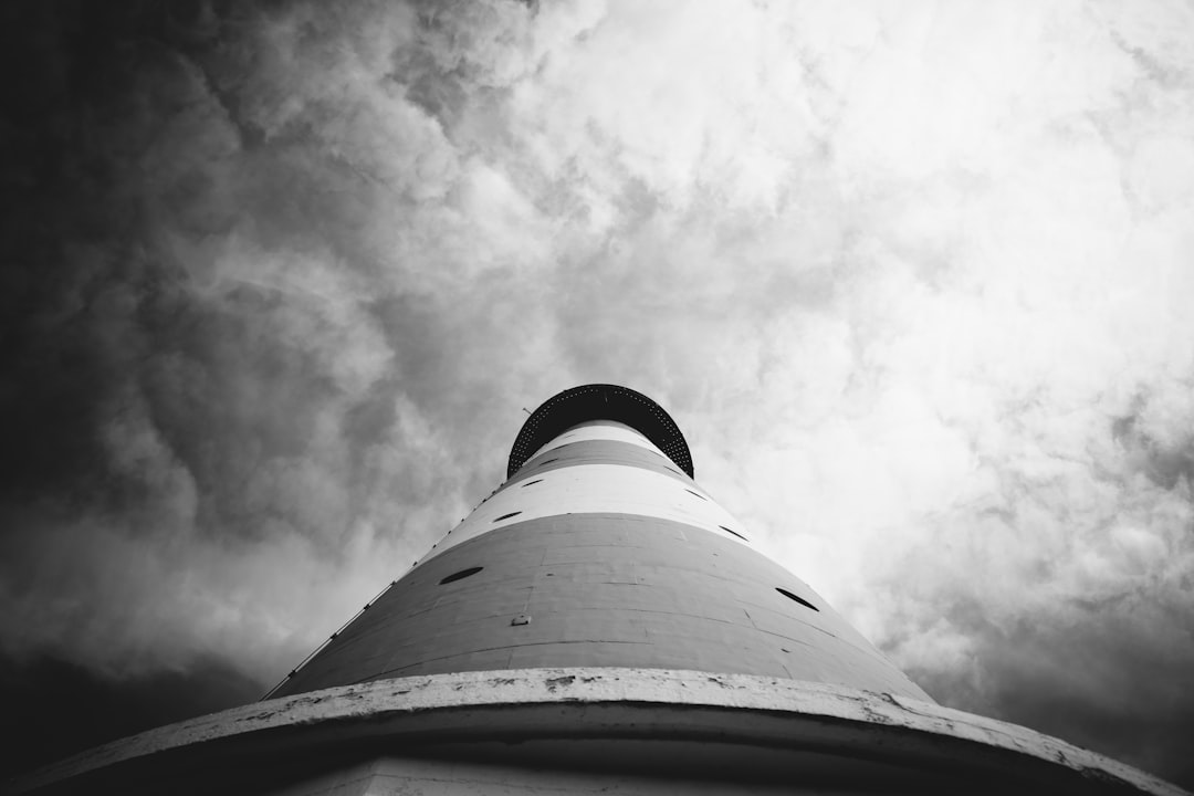 greyscale and low angle photography of lighthouse