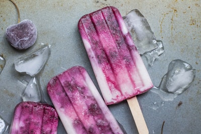 purple and white ice pop lying on wet ground with ice