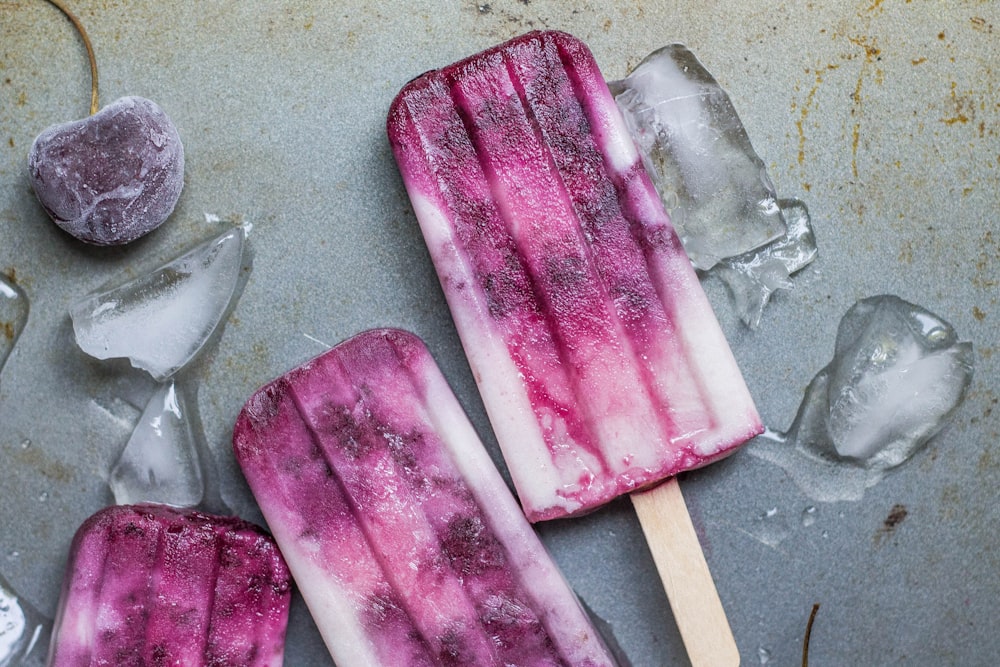 Éclat de glace violet et blanc couché sur un sol humide avec de la glace