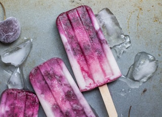 purple and white ice pop lying on wet ground with ice