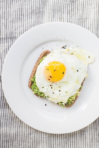 sunny side up egg, lettuce, bread on white ceramic plate