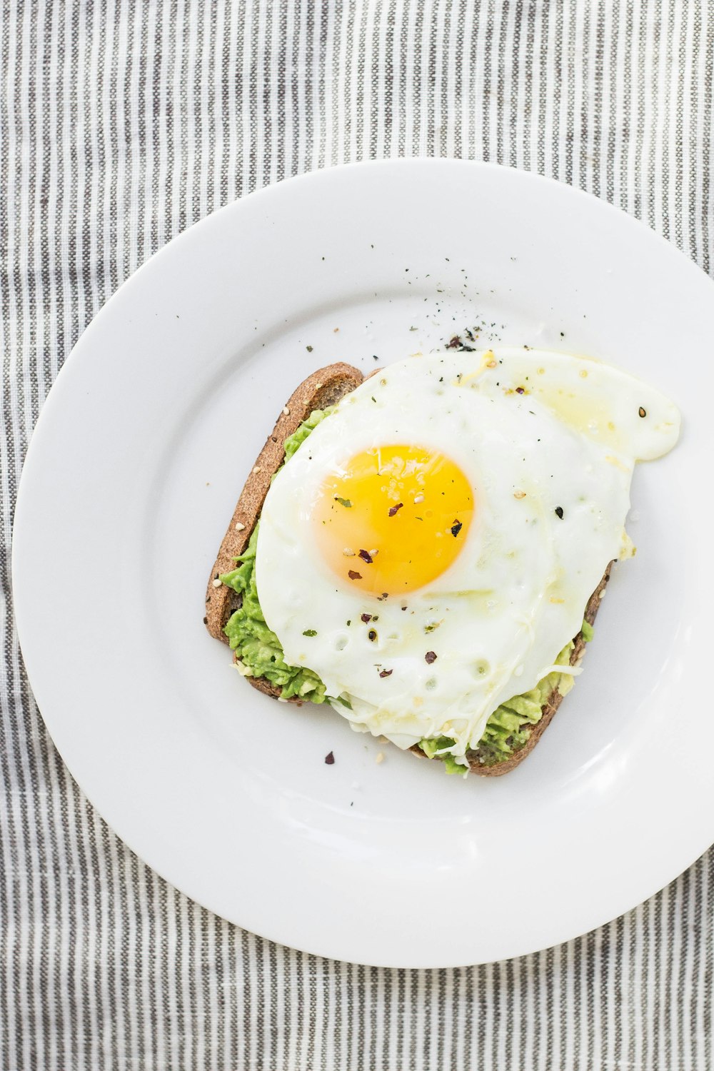 Oeuf au plat, laitue, pain sur assiette en céramique blanche