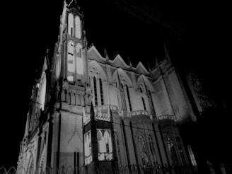 A Gothic-style architectural structure with intricate details and pointed arches, illuminated against a dark night sky.