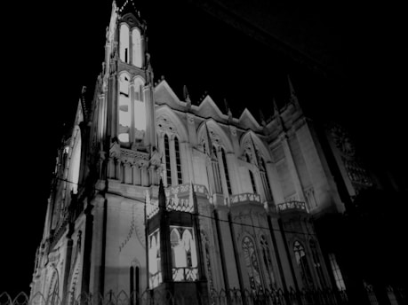 A Gothic-style architectural structure with intricate details and pointed arches, illuminated against a dark night sky.