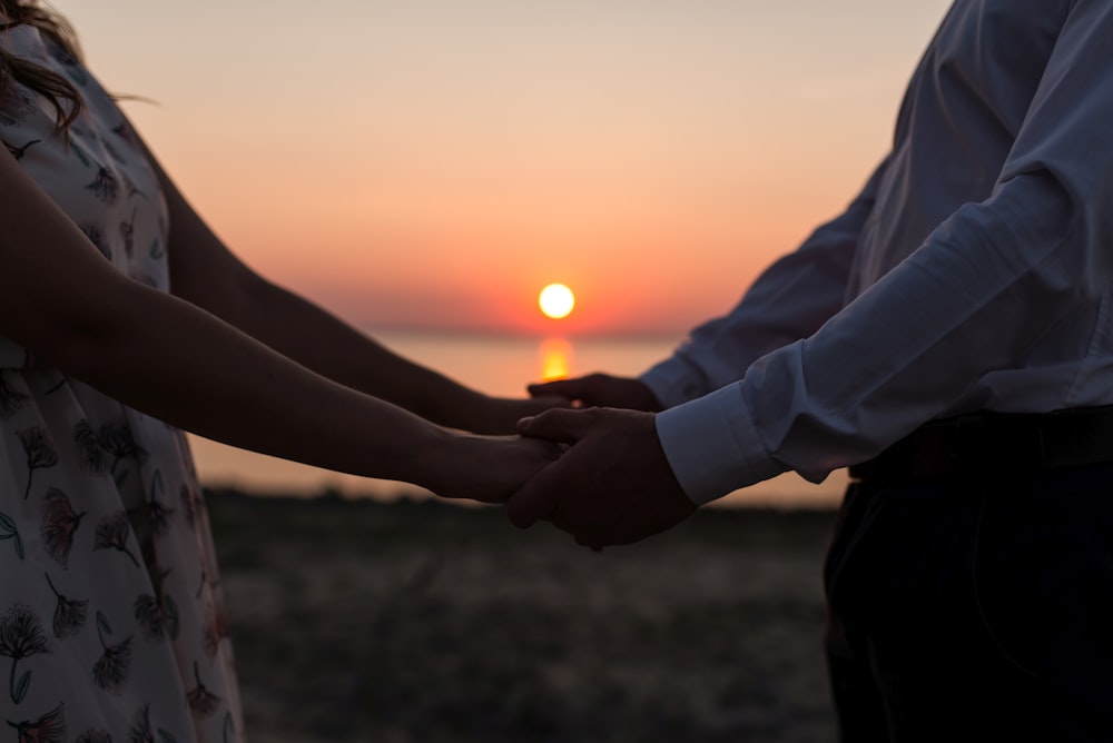 homem e mulher segurando as mãos um do outro