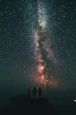 three person looking stars and milky way