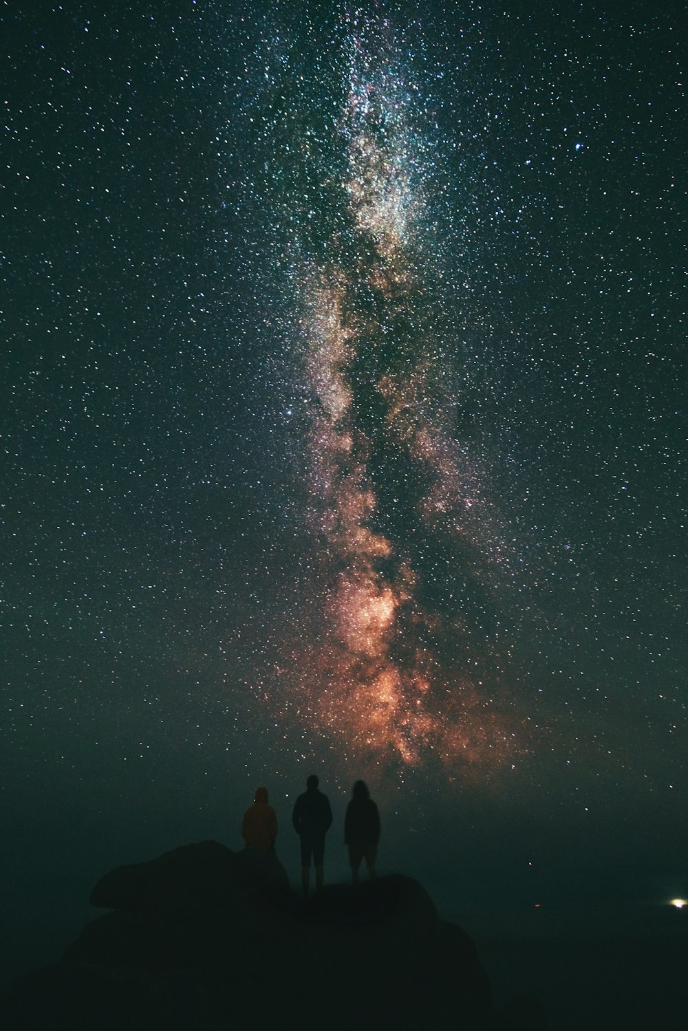 Tres personas mirando estrellas y Vía Láctea