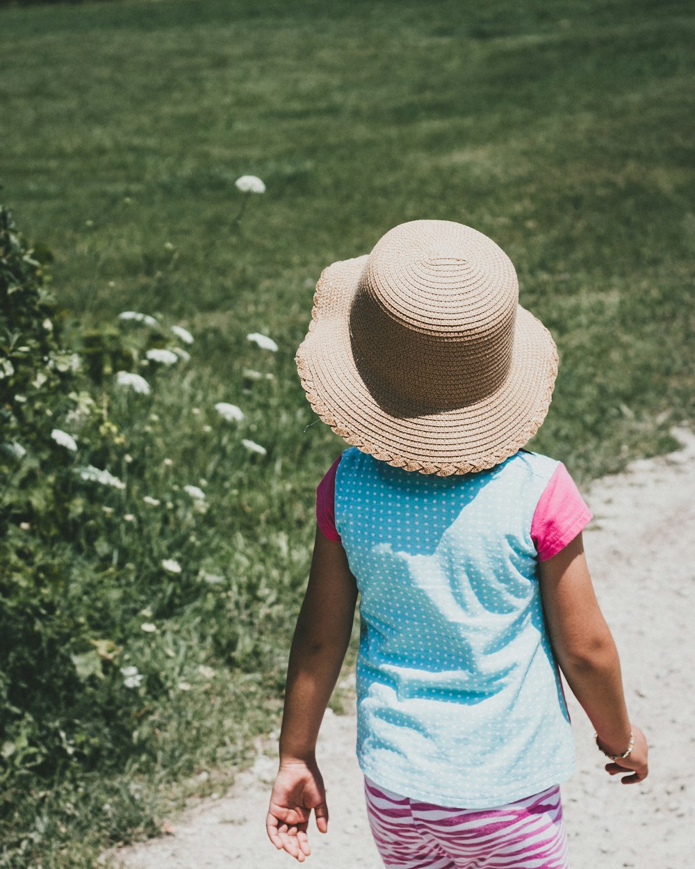 Menina que caminha perto do campo de grama verde