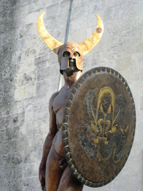 A cinematic portrait of a warrior wearing a horned helmet adorned with golden Ankh symbols.