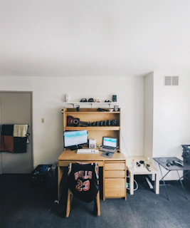 Organized dorm desk with monitor, storage shelf, and tidy cord management