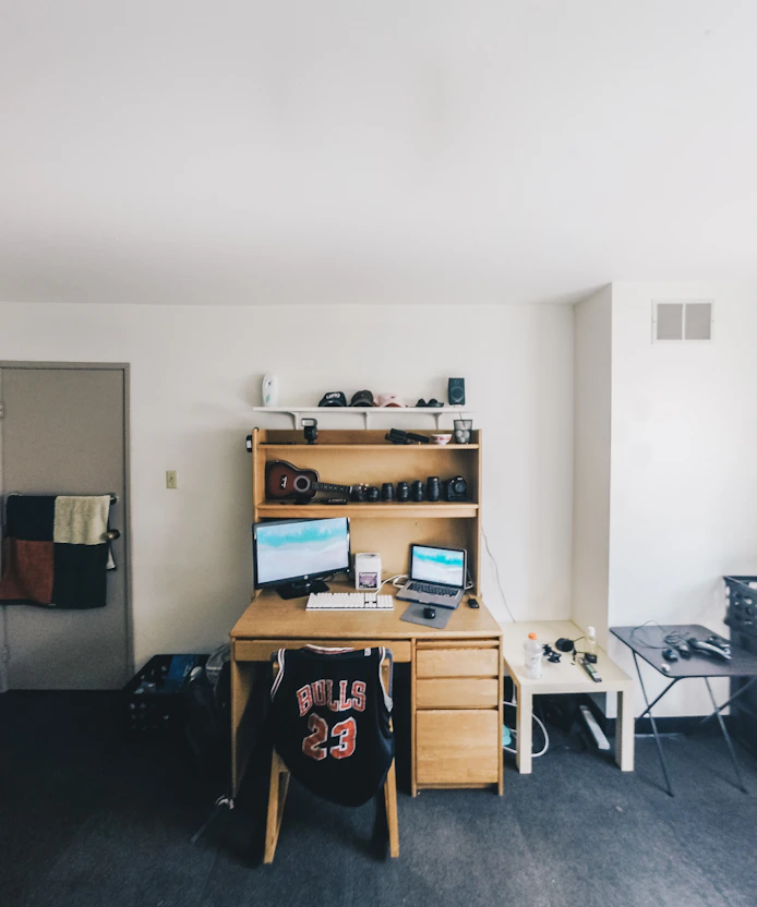 Organized dorm desk with monitor, storage shelf, and tidy cord management