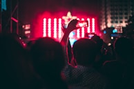 Fans holding up signs and phones at a concert, capturing the moment.