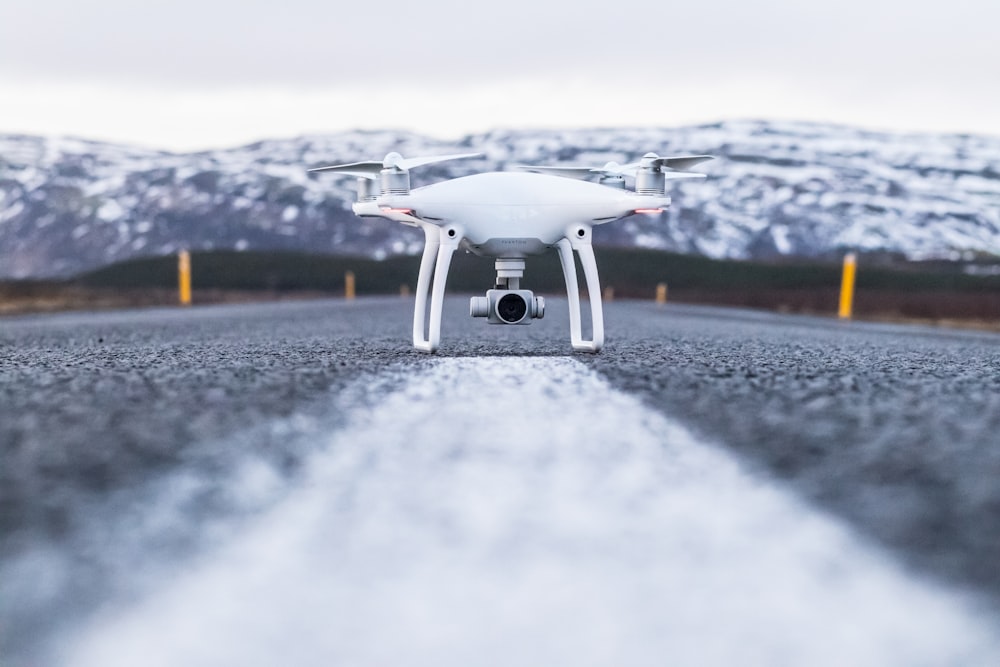 white quadcopter on gray concrete road top during daytime