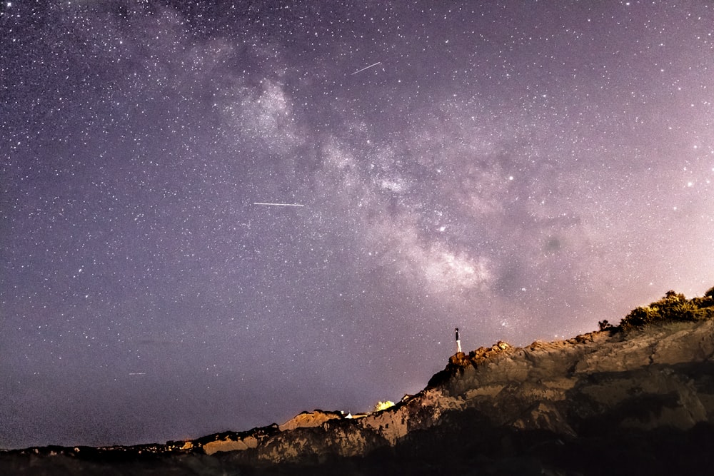 星空の下、岩の上に立っている人