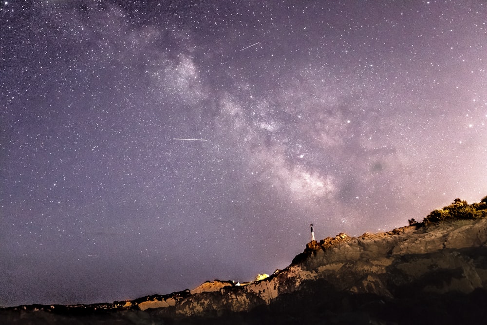 Persona de pie en la formación rocosa bajo el cielo estrellado