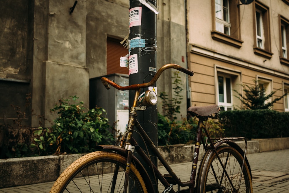 black and brown commuter bicycle beside black steel street post