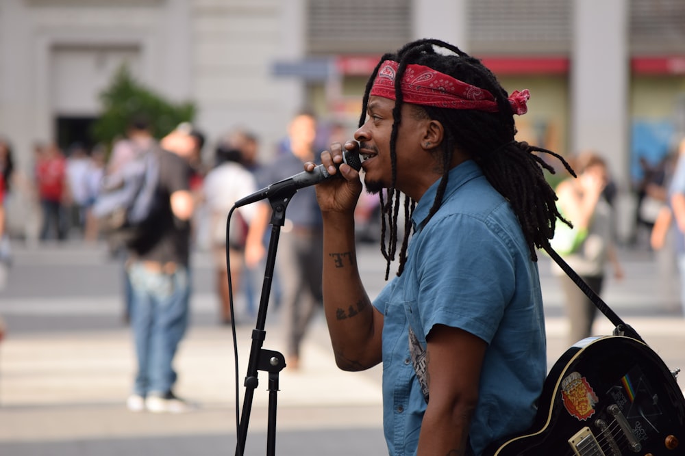 Selektive Fokusfotografie eines Mannes, der tagsüber ein Mikrofon in der Nähe von Menschen verwendet