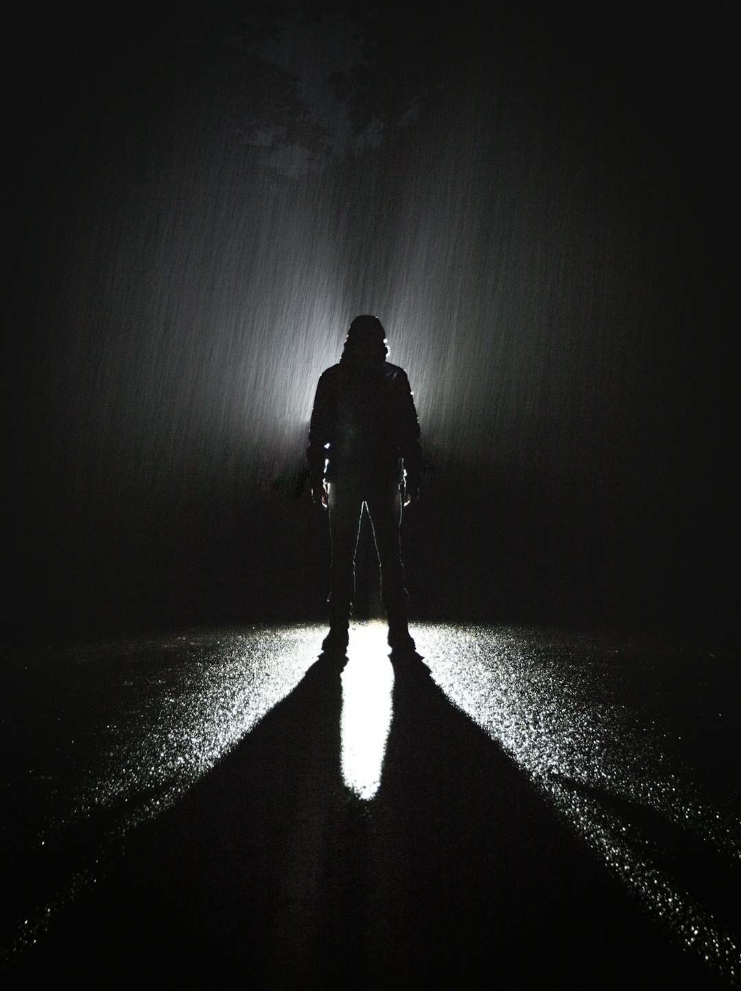 silhouette of person standing on road during rain