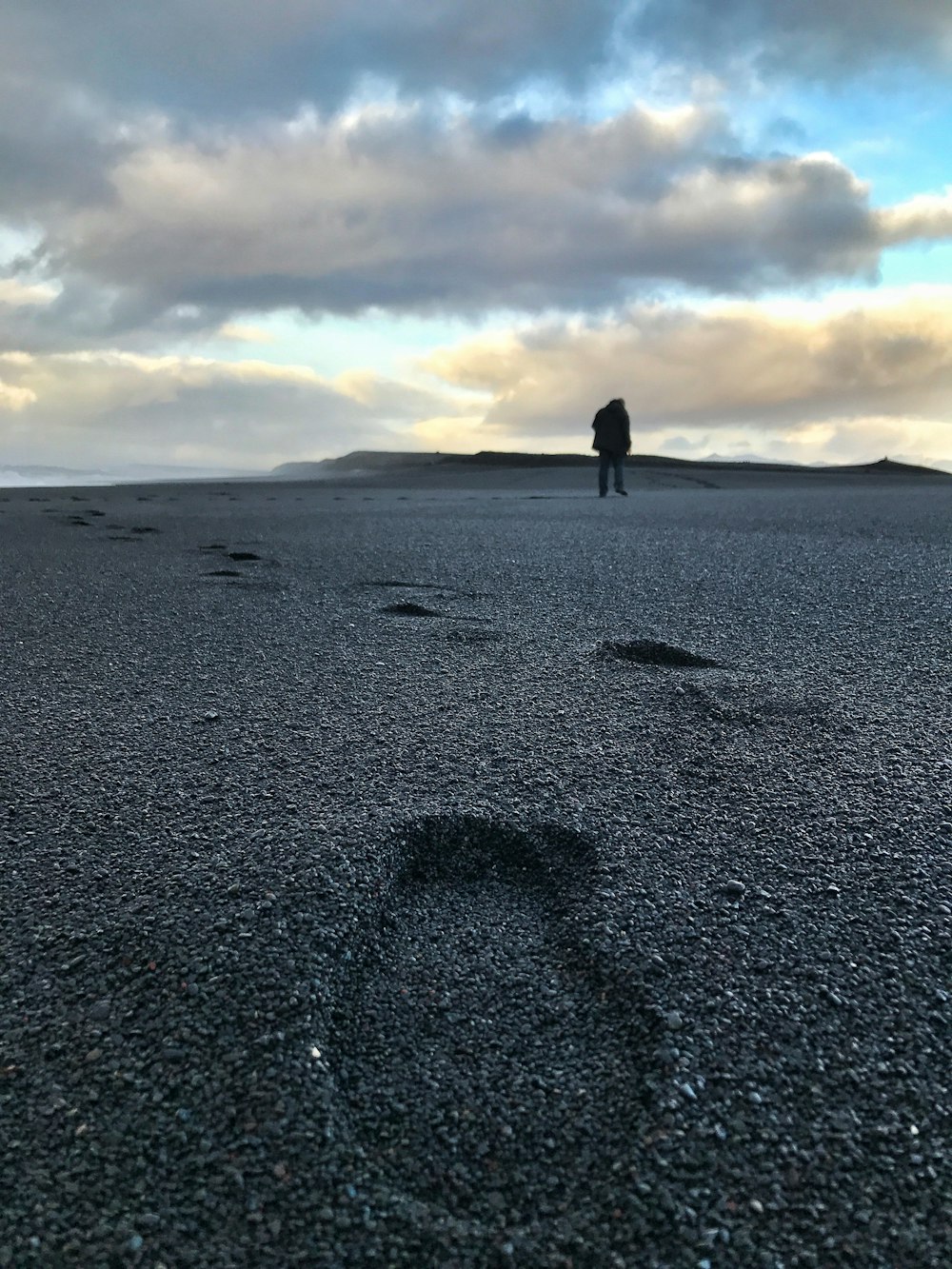 uomo in piedi sulla sabbia nera