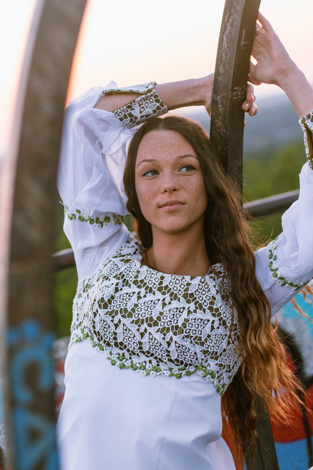 woman wearing white long-sleeved shirt leaning on black wood plank during daytime