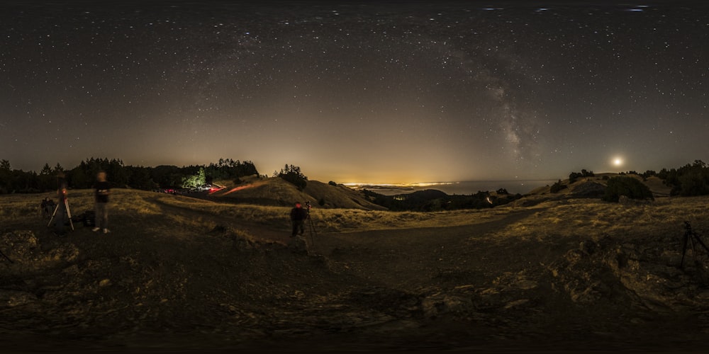 photographie de paysage de personnes campant sur une zone ouverte sous un ciel gris la nuit