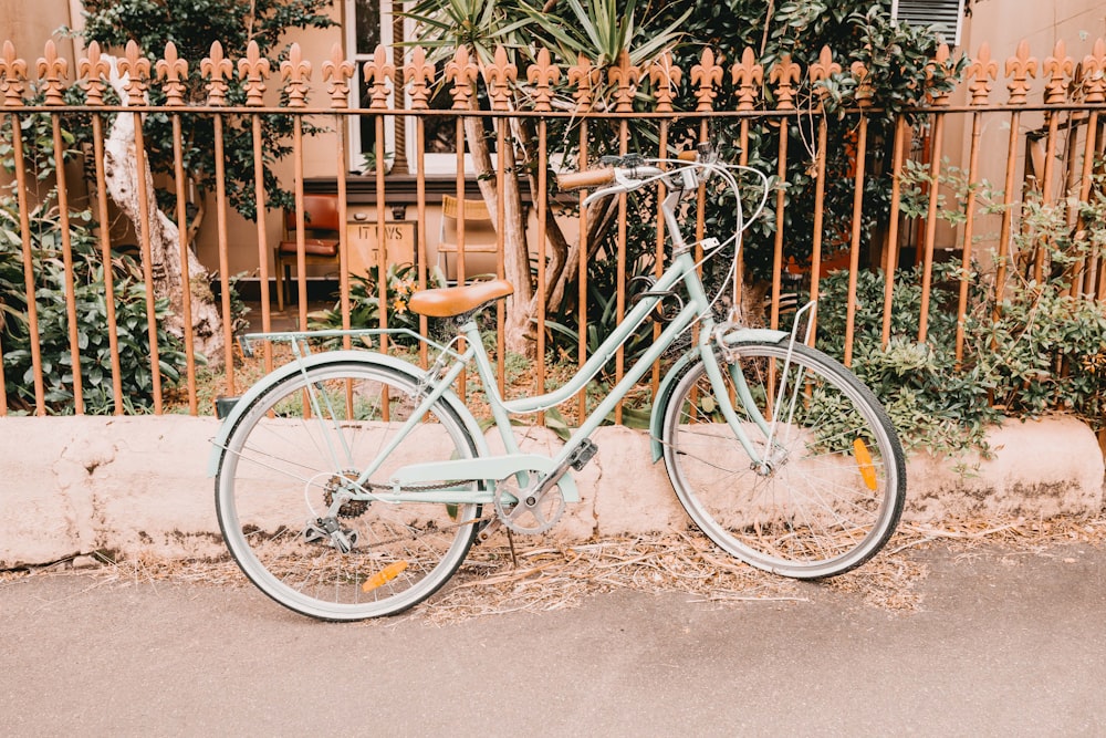 Bicicleta blanca con cuadro de paso estacionada al lado de la valla