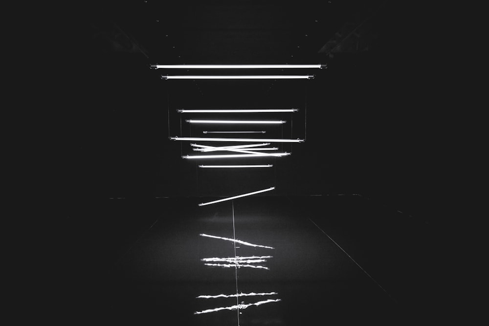 Uma foto única de luzes de tubo caindo do teto em um quarto escuro.