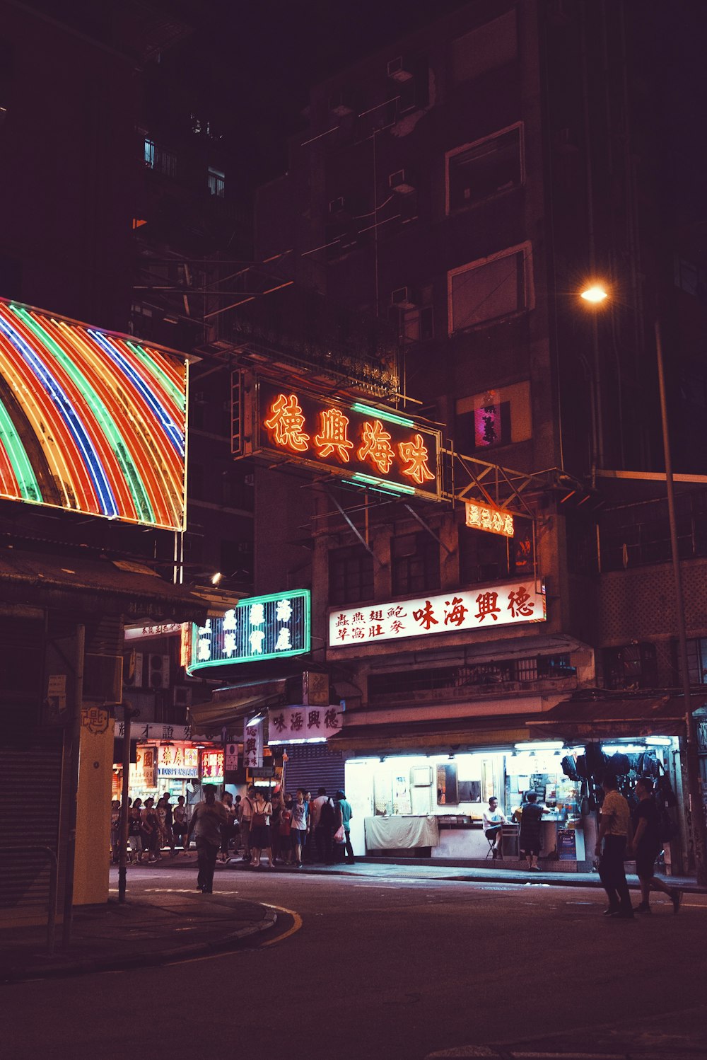 two person walking along the road under signage beside between buildings