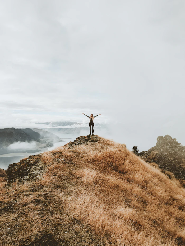 A woman standing alone on a hilltop, looking at the view