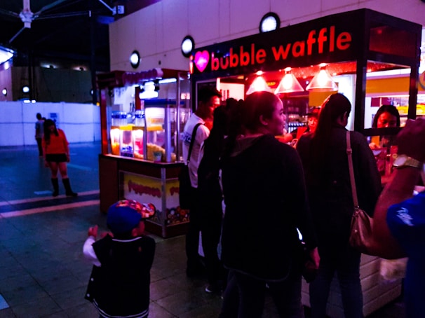 A vibrant orange and white food stall decorated with Panda Waffy branding at a lively outdoor fair.
