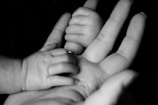 photo of baby holding person's fingers