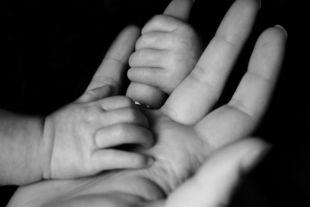 Foto eines Babys, das die Finger einer Person hält