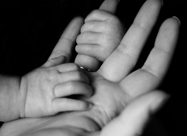 photo of baby holding person's fingers