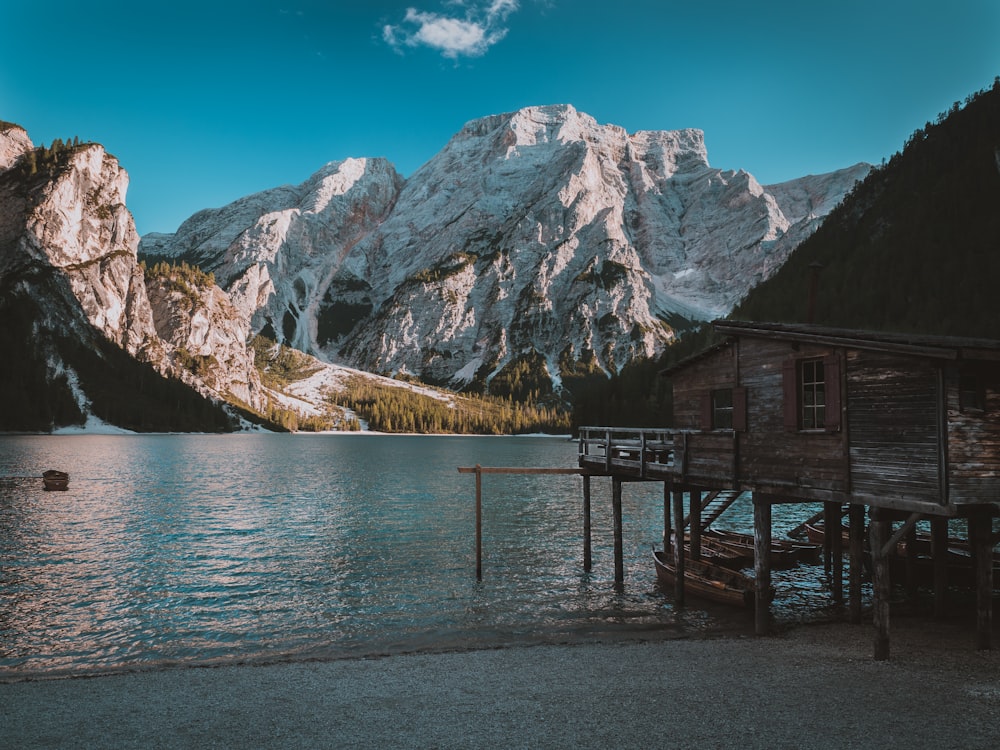 photo of wooden house near body of water and mountain