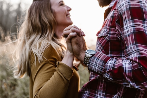 Best and Noon holding hands, smiling warmly against a backdrop of blush-toned decorations.