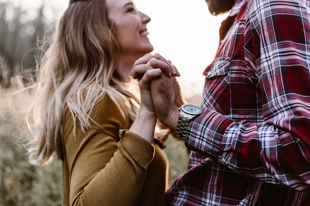 woman in front of man holding each hands each other near green trees