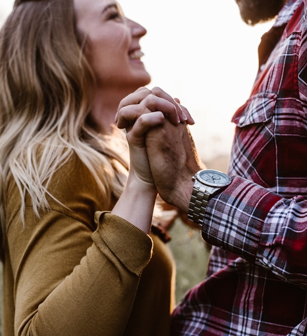 woman in front of man holding each hands each other near green trees