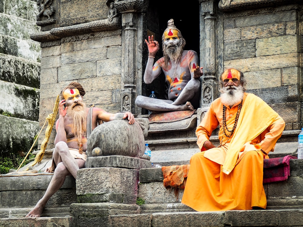 three monks sitting on concrete temple during daytime