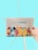 A hand is holding a newspaper with the headline 'Good Newspaper' in a modern design. The newspaper features colorful, abstract artwork with geometric shapes and a smiling face. The background is a solid light blue, creating a clean and minimalistic look.