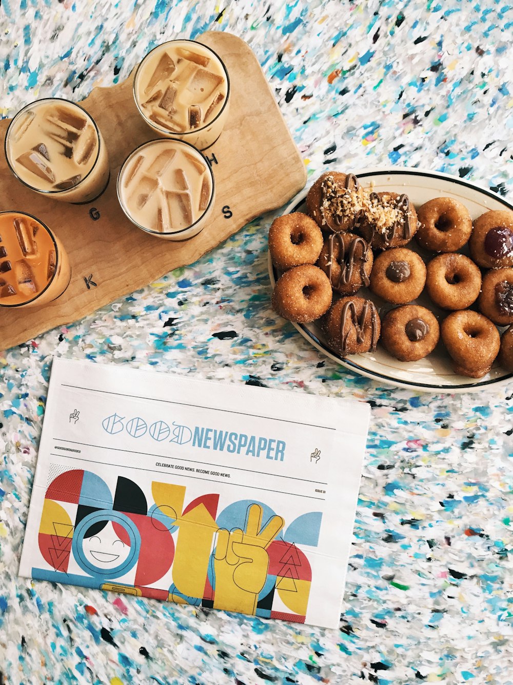 doughnuts on oval beige ceramic plate beside four glass cups on brown wooden board